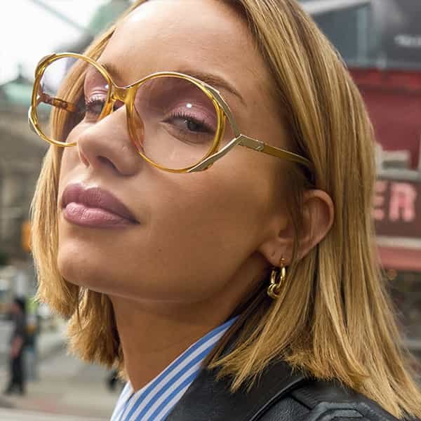 Femme blonde à lunettes, dont le visage est matifié par la poudre Fit Me Loose Powder